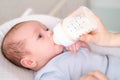 loving mother feeding her little boy child with milk baby bottle at home, portrait infant Baby eating, drinking powdered Royalty Free Stock Photo