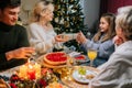 Loving mother giving festive box with Christmas present to adorable daughter sitting at dinner feast table during family Royalty Free Stock Photo