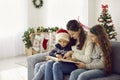 Loving mother with her children read book of stories in cozy bright living room on snowy winter day. Royalty Free Stock Photo