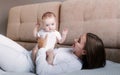 A loving mother and her little daughter. Young mother plays with her little beloved daughter on the couch