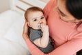 Loving mother holding cute infant baby in arms, little boy or girl with pacifier in mouth looking at camera, copy space Royalty Free Stock Photo