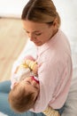 Loving mother holding her sleeping infant daughter on hands, lulling kid, sitting on bed, above view, vertical shot Royalty Free Stock Photo