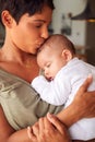 Loving Mother Holding And Kissing Sleeping 3 Month Old Baby Daughter In Kitchen At Home Royalty Free Stock Photo