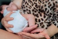 Loving mother holding tiny feet of newborn in hand near houseplant at home on sunny day. Maternity, motherhood concept. Royalty Free Stock Photo