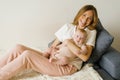 Loving mother holds her newborn baby in her arms at home, sitting on the couch Royalty Free Stock Photo