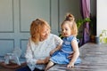 A loving mother plays with her child. Mother and daughter sit on the wooden floor near a large window. Royalty Free Stock Photo
