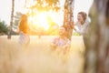 Loving mother plays with her daughter in the woods whilst her husband watches on