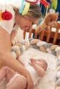 A loving mother puts her child in a crib with a musical toy. Mom hugs her baby. Happy childhood and motherhood. Royalty Free Stock Photo