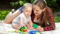 Loving mother relaxing at park with her baby son and playing toys on grass. Concept of child development, family having Royalty Free Stock Photo