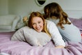 Loving mother and school kid girl making pillow fight together. Happy family, woman and cute daughter having fun Royalty Free Stock Photo