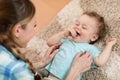 Loving mother tickling her little kid on carpet at home