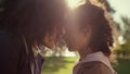 Loving mother touching noses with dreamy curly daughter golden sunlight closeup Royalty Free Stock Photo