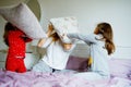 Loving mother and two little sisters girls making pillow fight together. Happy family, woman and cute daughters, toddler Royalty Free Stock Photo