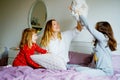 Loving mother and two little sisters girls making pillow fight together. Happy family, woman and cute daughters, toddler Royalty Free Stock Photo