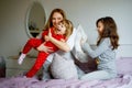 Loving mother and two little sisters girls making pillow fight together. Happy family, woman and cute daughters, toddler Royalty Free Stock Photo