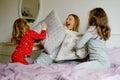 Loving mother and two little sisters girls making pillow fight together. Happy family, woman and cute daughters, toddler Royalty Free Stock Photo