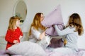 Loving mother and two little sisters girls making pillow fight together. Happy family, woman and cute daughters, toddler Royalty Free Stock Photo