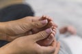 A loving new mother hands with a manicure gently holding and massaging her infant sons little feet. Close up Royalty Free Stock Photo