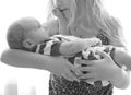 Loving older sister blonde sweetheart touching and gentle holds her newborn brother in her arms, cute tiny baby. Royalty Free Stock Photo
