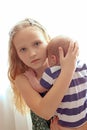 Loving older sister blonde sweetheart touching and gentle holds her newborn brother in her arms, cute tiny baby. Royalty Free Stock Photo