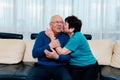 Loving older wife kissing smiling husband on cheek, expressing love and care, aged senior couple enjoying tender moment