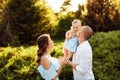 Loving overjoyed parents hold their adorable daughter