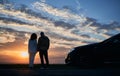 Loving pair with car watching romantic atmosphere of sunset. Royalty Free Stock Photo