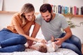 Loving Parents With Newborn Baby Lying On Bed At Home In Loft Apartment Royalty Free Stock Photo