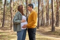 Loving pregnant woman and man walking in spring forest enjoying positive moments future father embracing big belly looking with Royalty Free Stock Photo