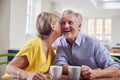 Loving Retired Couple Sitting Around Table At Home Having Morning Coffee Together Royalty Free Stock Photo