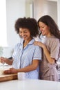 Loving Same Sex Female Couple Wearing Pyjamas Making Morning Pancakes In Kitchen At Home