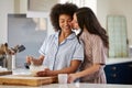 Loving Same Sex Female Couple Wearing Pyjamas Making Morning Pancakes In Kitchen At Home