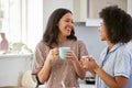 Loving Same Sex Female Couple Wearing Pyjamas Making Morning Pancakes In Kitchen At Home