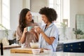 Loving Same Sex Female Couple Wearing Pyjamas Making Morning Pancakes In Kitchen At Home