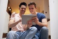 Loving Same Sex Male Couple Using Digital Tablet As They Relax At Home Together Royalty Free Stock Photo
