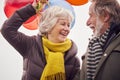 Loving Senior Couple Holding Balloons Enjoying Autumn Or Winter Walk Through Park Together Royalty Free Stock Photo