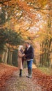 Loving Senior Couple Holding Hands As They Walk Along Autumn Woodland Path Through Trees Together Royalty Free Stock Photo