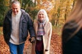 Loving Senior Couple Holding Hands As They Walk Along Autumn Woodland Path Through Trees Together Royalty Free Stock Photo