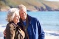 Loving Senior Couple Hugging As They Walk Along Shoreline Of Beach By Waves Royalty Free Stock Photo