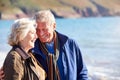Loving Senior Couple Hugging As They Walk Along Shoreline Of Beach By Waves Royalty Free Stock Photo