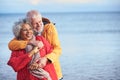 Loving Senior Couple Hugging As They Walk Along Shoreline On Winter Beach Vacation Royalty Free Stock Photo