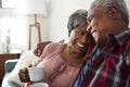 Loving Senior Couple Sitting On Sofa At Home Relaxing With Hot Drink Royalty Free Stock Photo