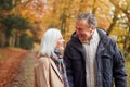 Loving Senior Couple Walking Along Autumn Woodland Path Through Trees Together Royalty Free Stock Photo