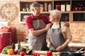 Loving senior couple wearing aprons and embracing in kitchen Royalty Free Stock Photo