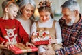 Loving senior grandparents give wrapped xmas gifts to happy grandchildren on Christmas morning Royalty Free Stock Photo