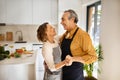 Loving senior husband and wife dancing in kitchen interior, elderly spouses having fun, enjoying time together at home Royalty Free Stock Photo