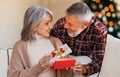 Loving senior man husband giving Christmas present gift box to happy surprised wife Royalty Free Stock Photo
