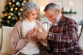 Loving senior man husband giving Christmas present gift box to happy surprised wife Royalty Free Stock Photo