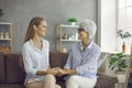 Happy senior mother together with her adult daughter sitting on sofa and holding hands Royalty Free Stock Photo