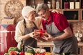 Loving senior woman giving gift box to her husband at kitchen Royalty Free Stock Photo